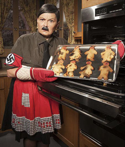 Roseanne is dressed 
like a German housewife, but with a swastika on her arm. She is pulling a batch of burnt, person-shaped cookies
out of an oven.