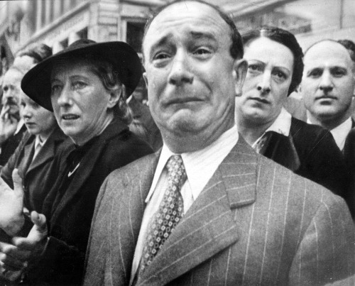 A middle-aged French gentleman
with dark hair and a gray pinstriped suit, in tears