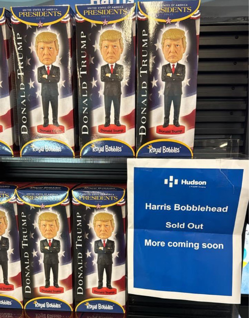 The shelf has lots of Trump bobbleheads,
and a sign explaining that Harris bobbleheads have sold out