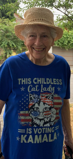 Woman wearing a shirt that says:
'THIS CHILDLESS Cat Lady IS VOTING KAMALA'