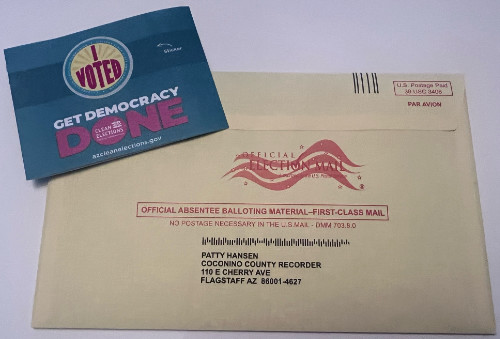 An Arizona absentee ballot, plus
a card with an 'I Voted' sticker with the words in large magenta letters and a sunburst pattern in the background