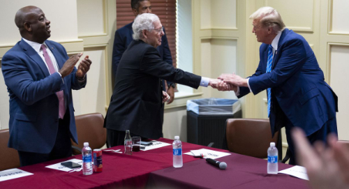 Trump shakes hands with Mitch 
McConnell, who is standing about as far away as possible while still making contact