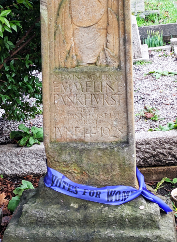 The headstone says: 'IN LOVING MEMORY OF
EMMELINE PANKHURST, WIFE OF R.M. PANKHURST, MD, AT REST JUNE 14, 1928' and it is adorned with a 'Votes for Women' sash.