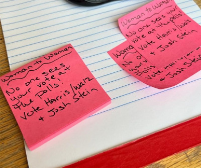 A bunch of Post-it Notes on a table say things like:
'Woman to woman, No one sees your vote at the polls! Vote Harris/Walz and Josh Stein'