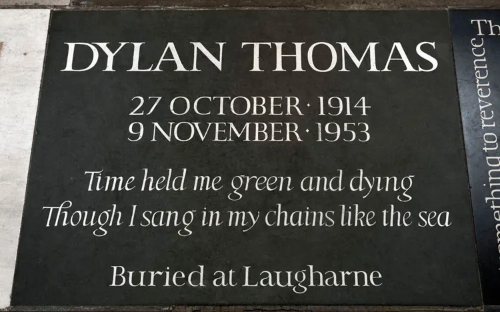 A black stone with 
silver lettering reads: DYLAN THOMAS. 27 OCTOBER 1914 9 NOVEMBER 1953. Time held me green and dying.
Though I sang in my chains like the sea. Buried at Laugharne.